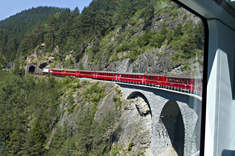 Innenansicht eines Schweizer Glacier-Express-Zugs, der über ein hohes Viadukt in einen Tunnel fährt